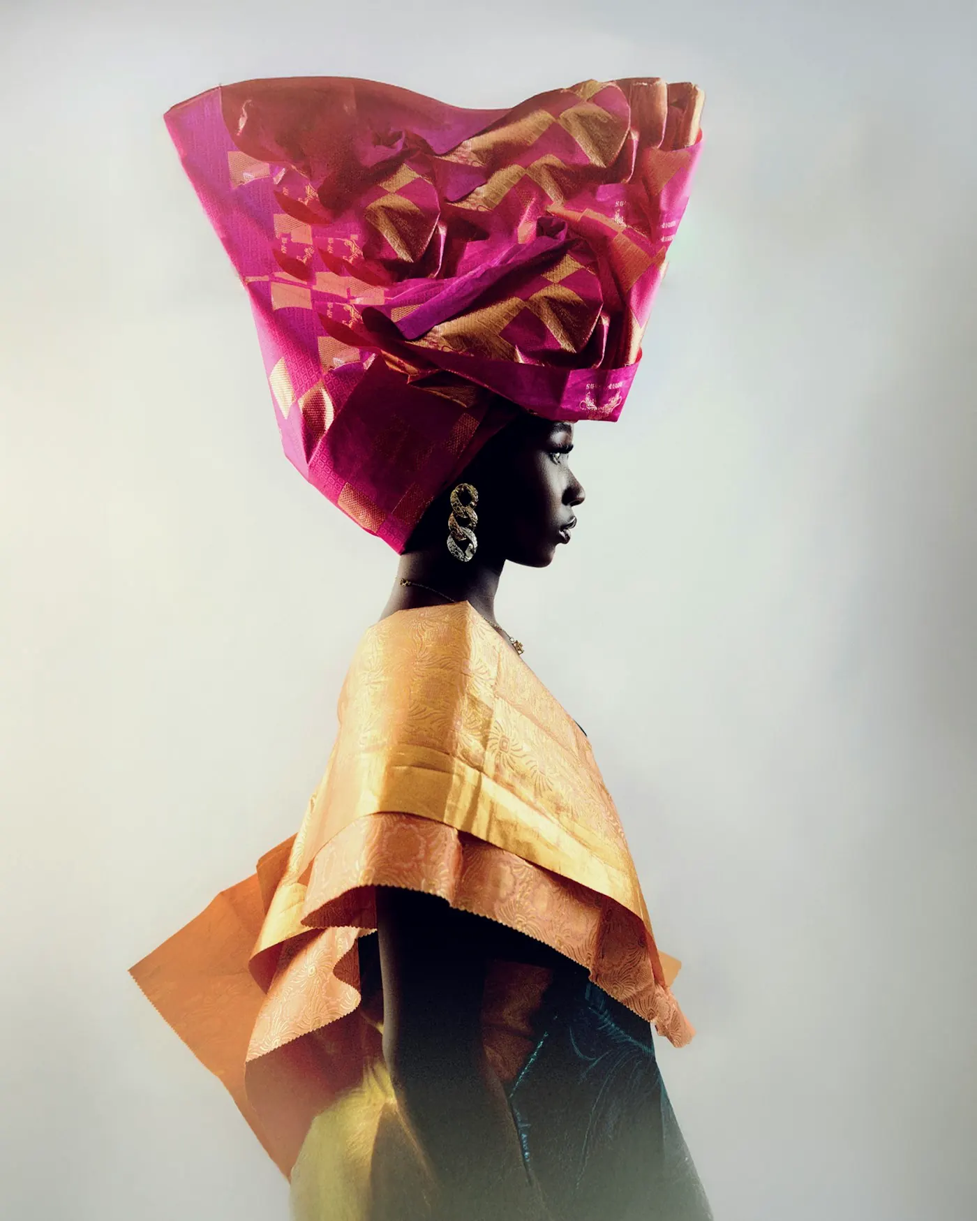 Back view of a model wearing a towering pink and gold headpiece.