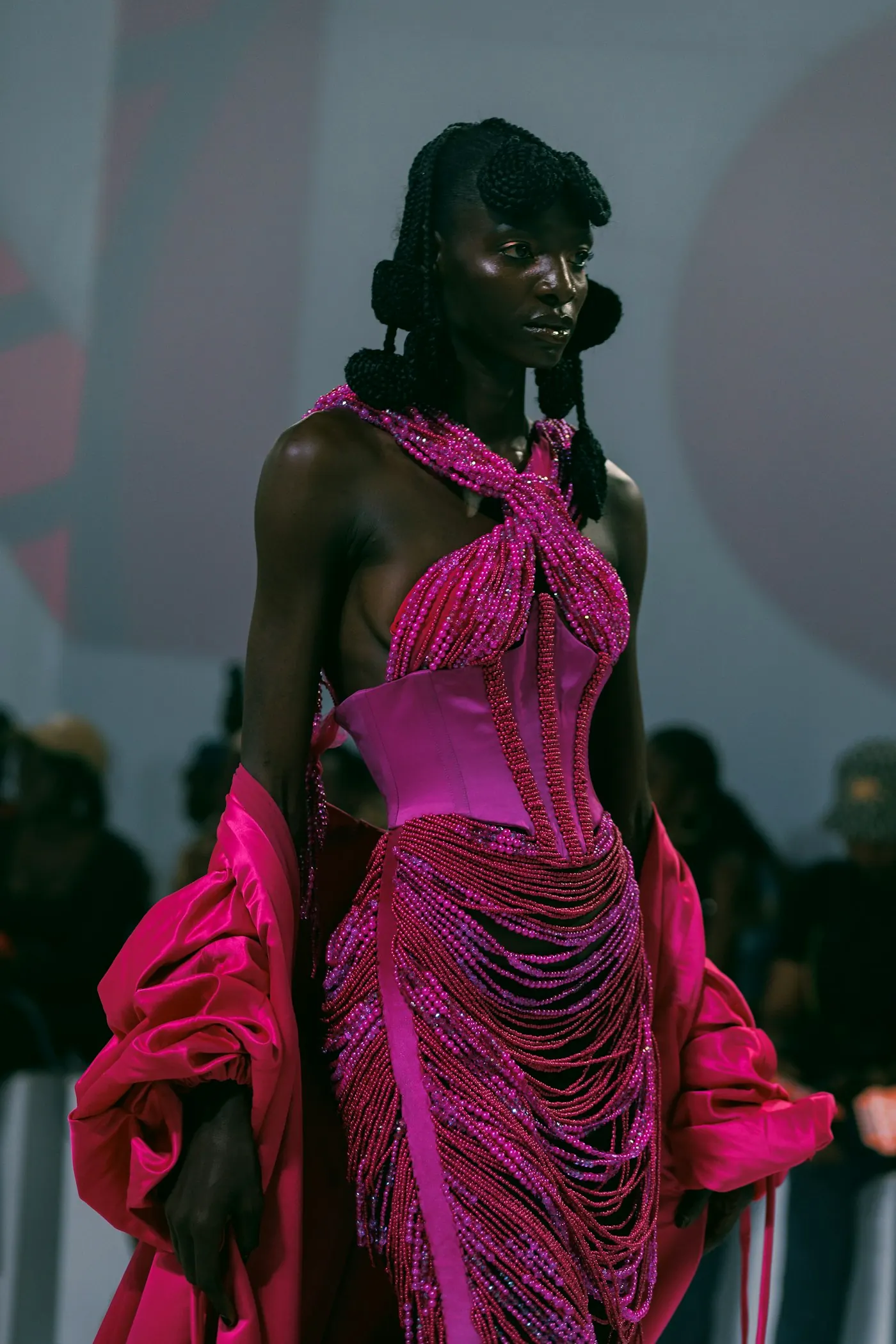 Model in a magenta fringed gown on the runway.