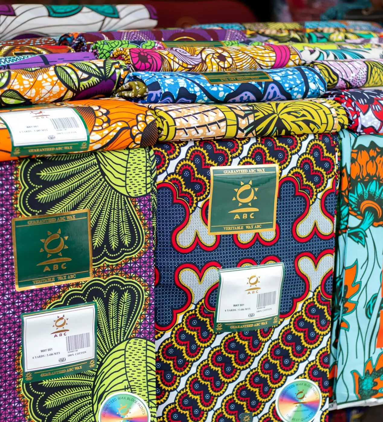 Close view of folded African print cloth with a dense floral pattern.